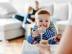 Guía para darle alimentos sólidos a tu bebé Bebé en su silla comiendo alimentos sólidos