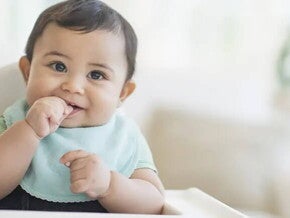 Bebé de 9 meses sentado sonriendo.