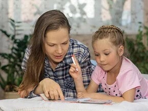 Conoce los diferentes estilos de aprendizaje. Mamá explicando a su hija por medio de un libro.