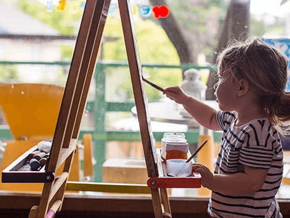 Niña pequeña pintando con pinturas en un lienzo.
