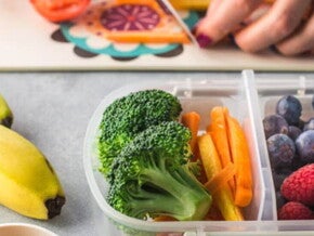 Plato de bananas, brócoli, bastones de zanahoria, arándanos y frambuesas, frutas y verduras con vitaminas y minerales.