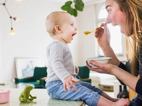 Mamá alimentando con una cuchara a su hijo pequeño con probióticos