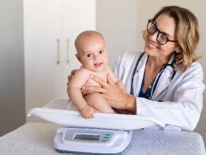 La tabla de peso en niños es un herramienta muy útil. Doctora pesando al bebé.