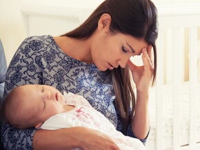 Mujer con depresión posparto cansada y sosteniendo a su bebé. 