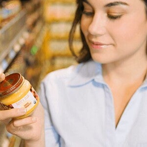 Mujer leyendo etiqueta nutricional con un frasco de colado para bebes