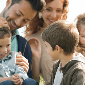 Una familia ensamblada con tres niños disfrutando juntos en el césped.