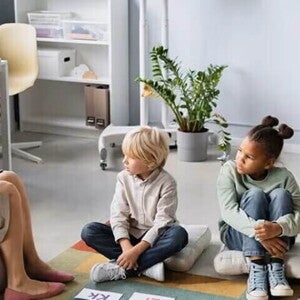 Patólogo del habla y lenguaje, SLP terapeuta del habla y lenguaje, fonoaudiólogo mostrando abecedario a niños pequeños sentados sobre cojines.