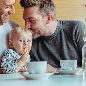 Conoce cuándo puedes darle galletas para bebés a tu hijo. Niña comiendo galletas para bebés con su papá y abuelo.