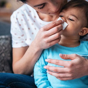 Es importante descongestionar la nariz de un bebé para su correcta respiración. Mujer descongestionando la nariz de un bebé.