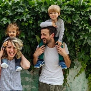 Estilos de crianza para educar a mi hijo. Los padres riendo con los hijos alzados.