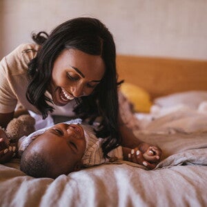 La mamá y el bebé haciendo ejercicios en la cama La mamá y el bebé haciendo ejercicios en la cama