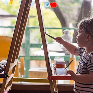 Niña pequeña pintando con pinturas en un lienzo.