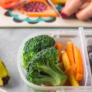 Plato de bananas, brócoli, bastones de zanahoria, arándanos y frambuesas, frutas y verduras con vitaminas y minerales.