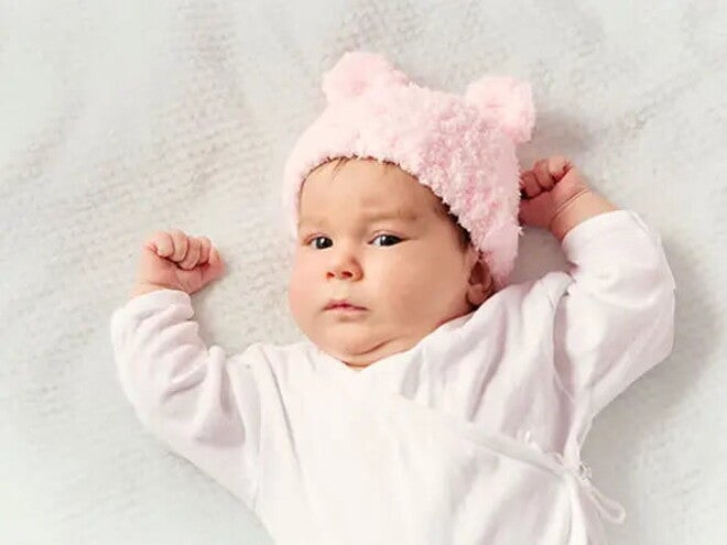 Bebé de dos meses acostada sobre la cama.