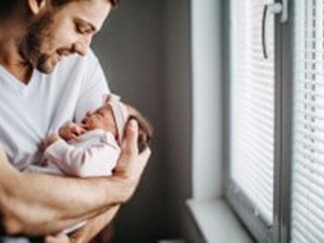 Los granitos en la cara de los bebés es un fenómeno común Papá alzando su bebé y revisando los granitos de su cara