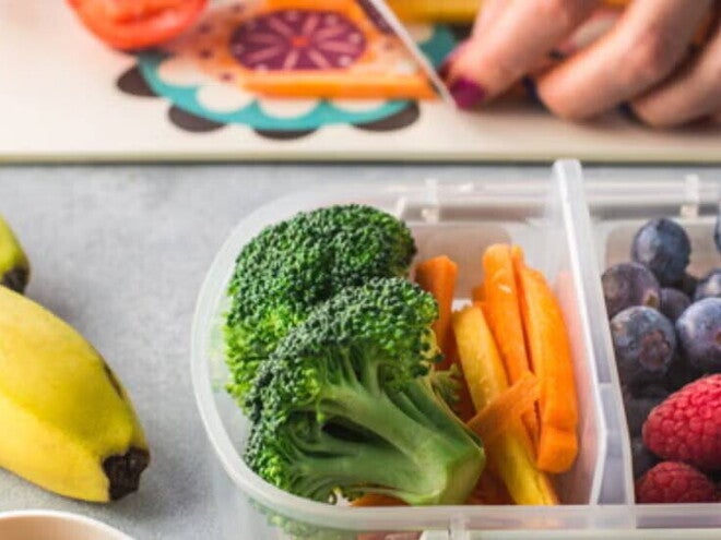 Plato de bananas, brócoli, bastones de zanahoria, arándanos y frambuesas, frutas y verduras con vitaminas y minerales.