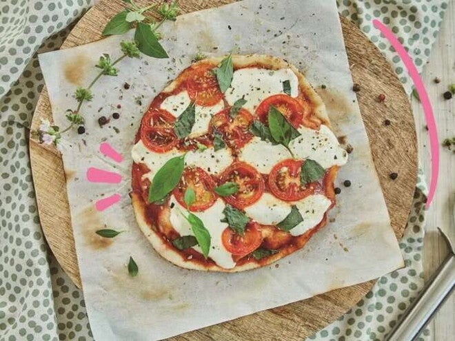 Pizza al estilo Margarita con Pan Árabe Pizza margarita en el centro con decoración de queso y albahaca alrededor