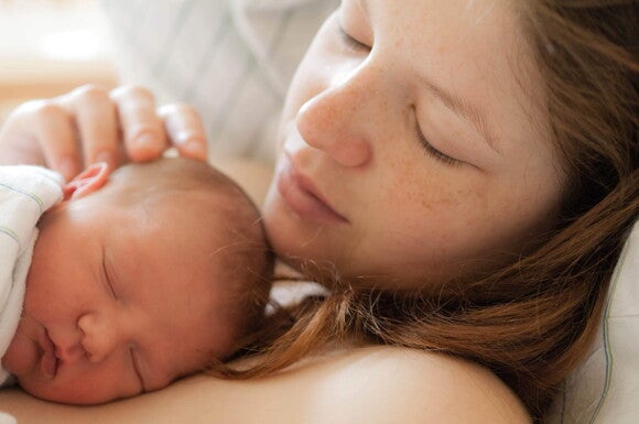 Madre acostada en la cama con su bebe Vínculo y el Desarrollo Emocional