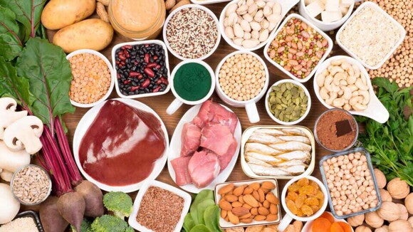 Platos de alimentos ricos en hierro como carnes, frutos secos, leguminosas y hojas verdes