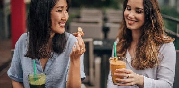 Las bebidas gaseosas poseen alto contenido de azúcar y no se debe consumir en la lactancia. Dos mujeres tomando bebidas gaseosas.