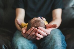 Una de las causas de los granitos en la cara de los bebés son las hormonas maternas Papá alzando su bebé en sus piernas