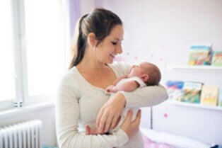 Uno de los cuidados que debes tener para los granitos en la cara del bebé es la limpieza Mamá alzando a su bebé y mirando su cara