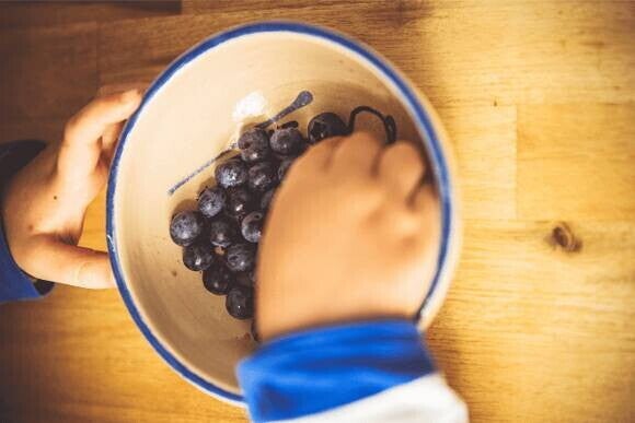 Snacks para el Día del Niño niño comiendo uvas de un recipiente