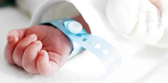 Ideas de nombres para bebés varones Mano de bebé varón recién nacido con pulsera azul de hospital.