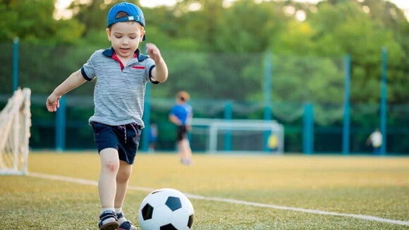 Niño pequeño jugando fútbol en una cancha.