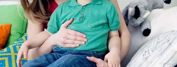 Niño intolerante a la lactosa poniendo su mano sobre su barriguita.