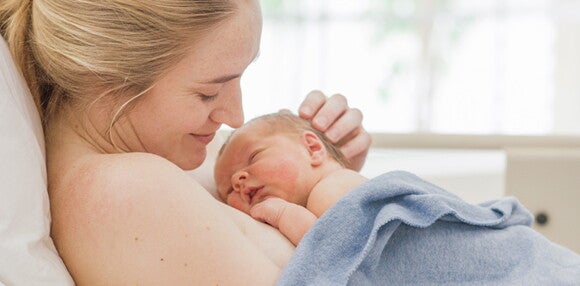 Existen varios motivos por los cuales el médico sugiere un parto inducido. Mamá teniendo a luz a su bebé por parto inducido.