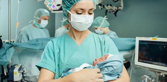 Los médicos son fundamentales para la tranquilidad de la mamá en la inducción del parto. Enfermera alzando al bebé luego del parto inducido.