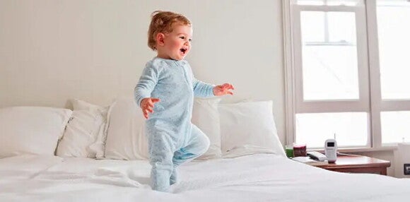 Conoce las rutinas y pautas en un bebé de 18 meses. Bebé de 18 meses de pie en una cama.